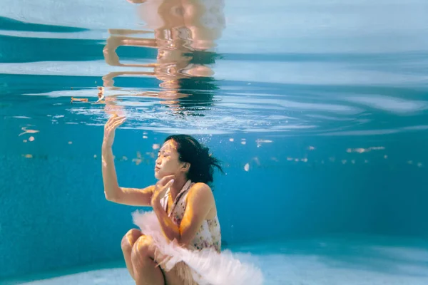 日本芭蕾舞演员正在水下跳舞 背景是气泡和漂浮的树叶 她在水中的倒影是可见的 — 图库照片