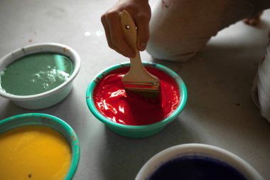 Adam elinde fırça ile Oda onarmak için kase kırmızı boya karıştırır. Üstten görünüm. Portre. Onarım kavramı.