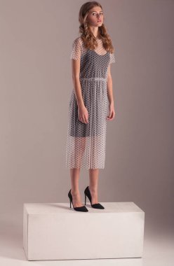 Studio pembe bir arka plan üzerinde elbise şeffaf ve stiletto topuklar genç model poz.