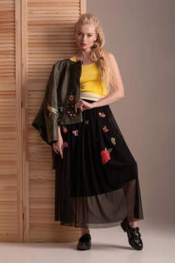 Oyma siyah etek ve deri ceketli sarışın model studio poz.