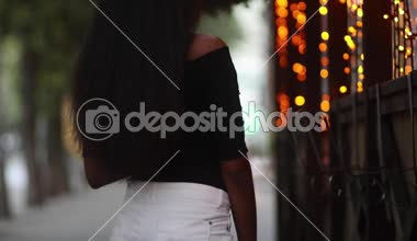 Kahve onun elinde olan kadın vitrin çelenk ve akşam saatlerinde gülümseyen ile yakın duruyor. Bokeh etkisi.