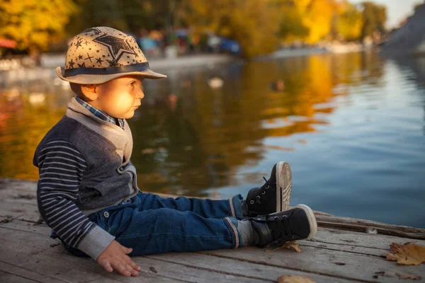 Ein Kleiner Junge Sitzt Neben Dem See Bei Einem Spaziergang — Stockfoto