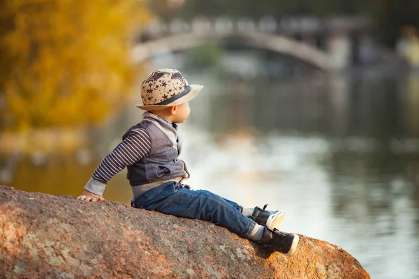Ein Kleiner Junge Sitzt Auf Einem Felsen Neben Dem See — Stockfoto