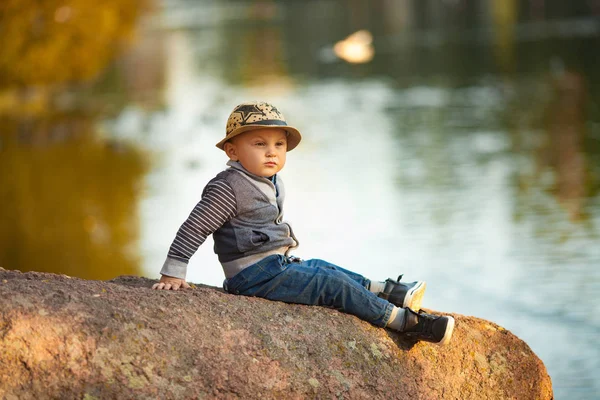Ein Kleiner Junge Sitzt Auf Einem Felsen Neben Dem See — Stockfoto