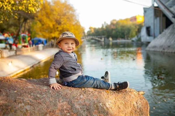 Chlapeček Sedí Skále Jezera Během Procházky Parku Pozadí Žluté Podzimní — Stock fotografie