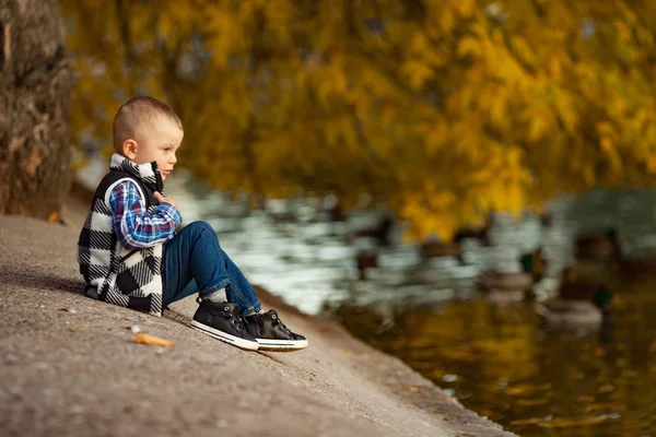 Menino Está Sentado Uma Rocha Lado Lago Durante Passeio Parque — Fotografia de Stock