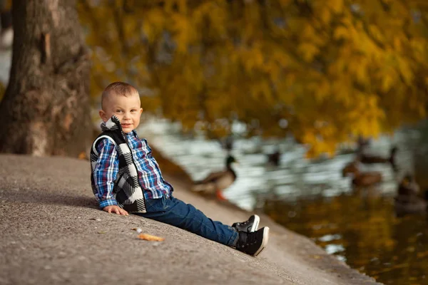 Liten Pojke Sitter Klippa Intill Sjön Promenad Parken Mot Bakgrund — Stockfoto