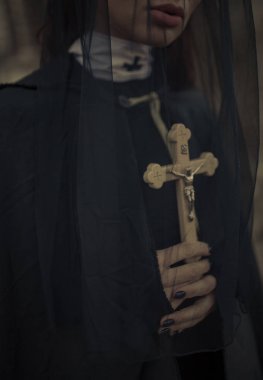 Güzel genç Rahibe siyah cüppe, pelerin ve şeffaf cape olduğunu ayakta ve dua ile çapraz onun elinde. Portre.