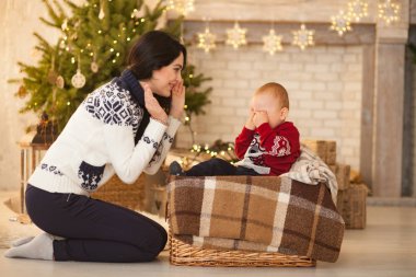 Anne küçük ağlayan oğlu Noel ağacı ve festival çelenk arka plan üzerinde konfor.