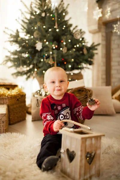 元気な子少年は クリスマス ツリーとお祝い花輪の背景に子供たちのおもちゃの車に座っています 黒と白のイメージ — ストック写真