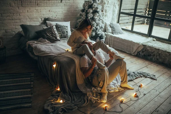 恋のベッドの近く楽しんで クリスマス ツリー 白熱電球 レンガの壁 ウィンドウの背景に抱いて若いカップル — ストック写真