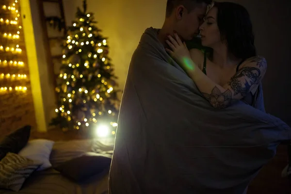 暗い部屋の装飾 クリスマス ツリー ベッドの背景にもてもてメルビン中抱擁は 若い恋人たち — ストック写真