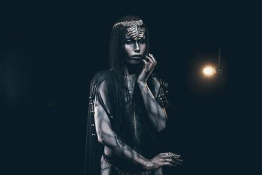 İnsansı ve dünya dışı yabancı onun baş ve desen ışık arka plan üzerinde sürüngen gibi vücudunda boynuzları ile görüntüdeki genç kadın.