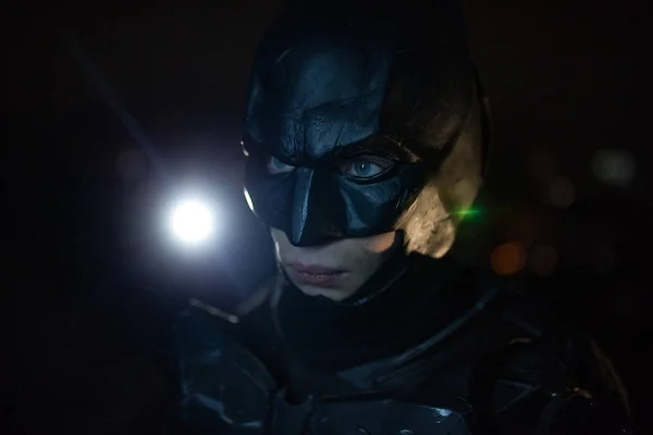 Maske, kask, zırh ve siyah pelerin giymiş bir adam gece ışık arka plan karşı duruyor. Cosplay. Portre.