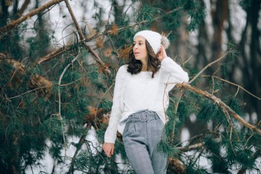 Genç kadın yanındaki çam ağacının gövde düşmüş kış ormanda yürüyüş sırasında duruyor.