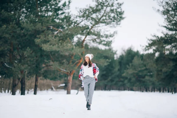一位年轻女子走过冬天的松树林 — 图库照片