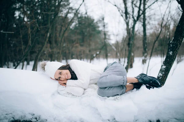在冬林散步时 年轻开朗的女子躺在雪堆上 面带微笑 — 图库照片