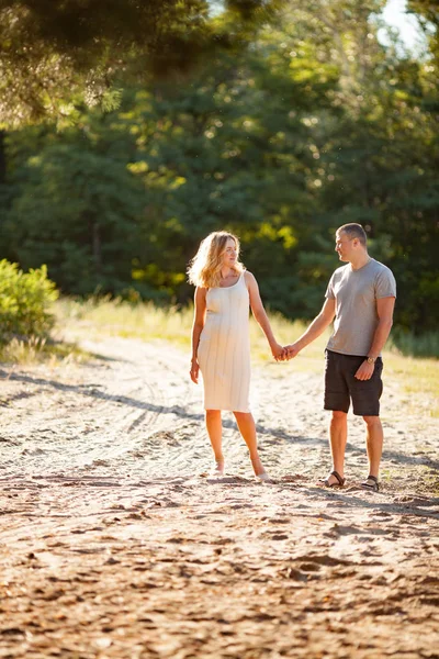 妊娠中の女性の晴れの日に森に散歩中に彼女の夫と手をつないで — ストック写真