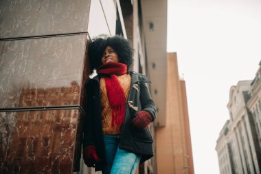 Genç siyah ayakta ve şehir sokak binasında yanında gülümsemek kadındır.
