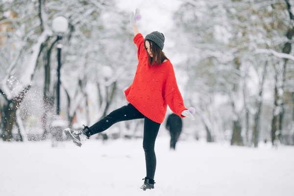 穿着红色毛衣的快乐女孩在雪街上散步时 她的腿上扔下了雪 — 图库照片