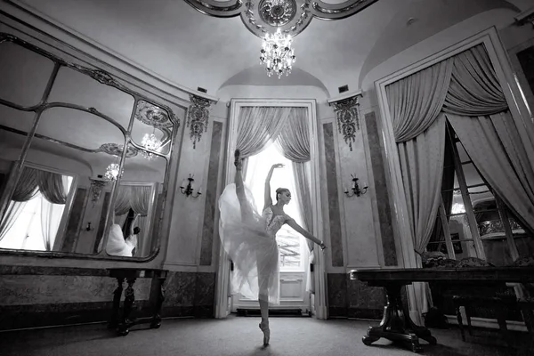 美丽的芭蕾舞演员在豪华的大厅里跳舞 窗户上有一个枝形吊灯和镜子 黑白图像 — 图库照片