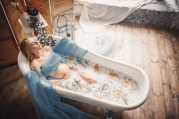 Mulher grávida toma um banho com leite, ervas de lavanda e laranja — Fotografia de Stock