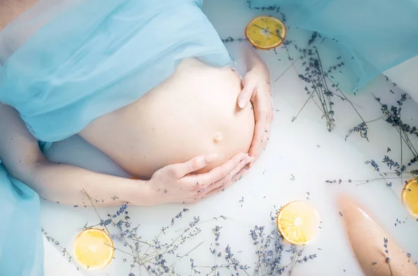 Femeia gravidă face baie cu lapte, ierburi de lavandă și portocaliu — Fotografie, imagine de stoc