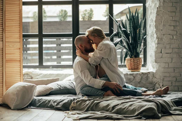 Zwangere vrouw knuffels met haar echtgenoot op een bed. — Stockfoto