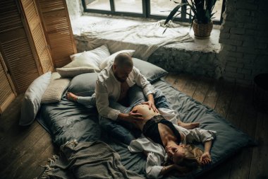 Genç adam bir karın hamile eşi bir yatakta dokunur.