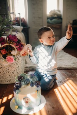 Toddler çocuk oturur üzerinde zemin yakın Doğum günü Cake.
