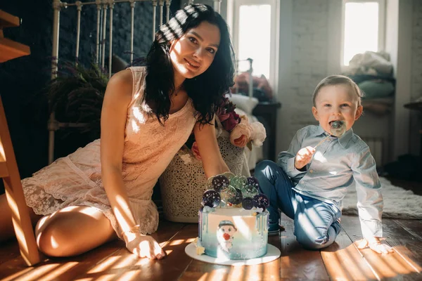 Bambino ragazzo si siede con la madre vicino torta di compleanno . — Foto Stock