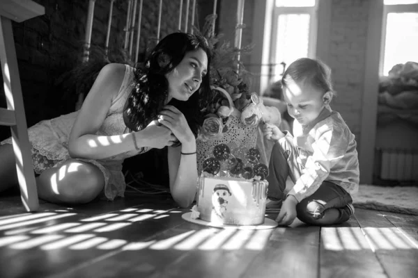 Menino da criança senta-se com sua mãe perto de bolo de aniversário . — Fotografia de Stock