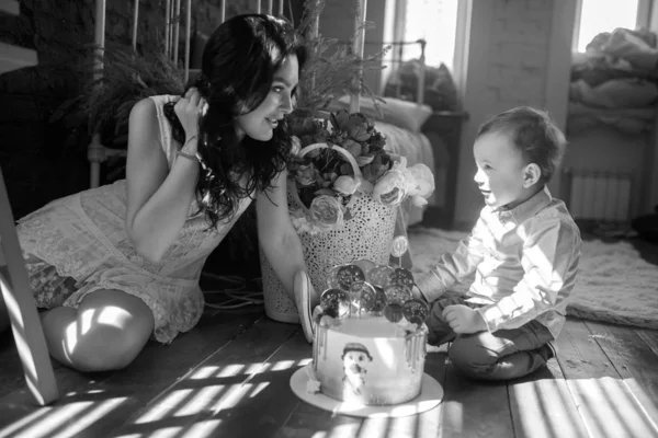 Menino da criança senta-se com sua mãe perto de bolo de aniversário . — Fotografia de Stock