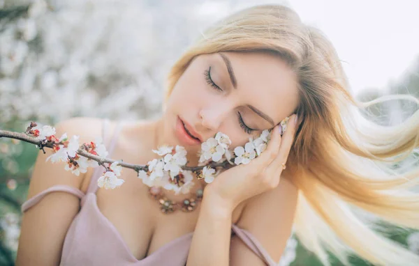 Portret van jonge vrouw onder de bloemen van abrikozenbomen. — Stockfoto