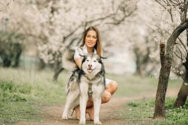 Genç bir kadın çiçekleme Bahçesi arasında köpeğin yanında oturur.