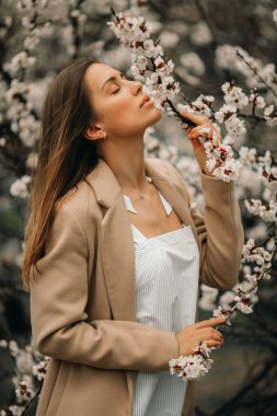 Çiçek açan kayısı ağaçları arasında genç bir kadının portresi.