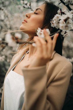 Çiçek açan kayısı ağaçları arasında genç bir kadının portresi.