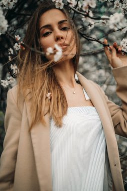 Çiçek açan kayısı ağaçları arasında genç bir kadının portresi.