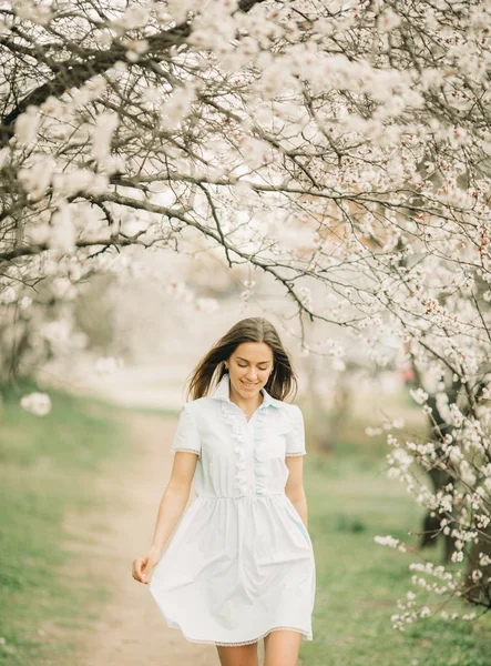 Een jonge vrouw loopt tussen de bloeiende tuin. — Stockfoto