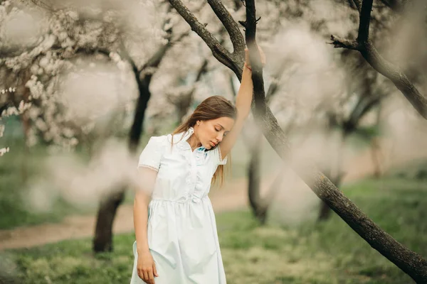 Una giovane donna triste è in mezzo al giardino fiorito . — Foto Stock