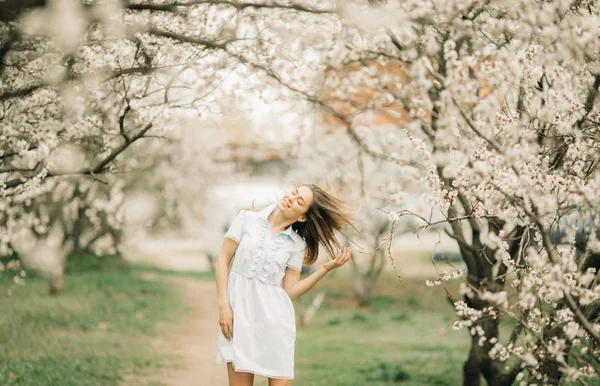 Молода жінка ходить серед квітучого саду . — стокове фото