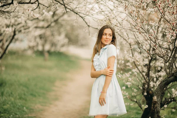 Eine junge Frau steht im blühenden Garten. — Stockfoto