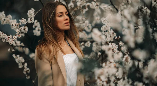 Çiçek açan kayısı ağaçları arasında genç bir kadının portresi.