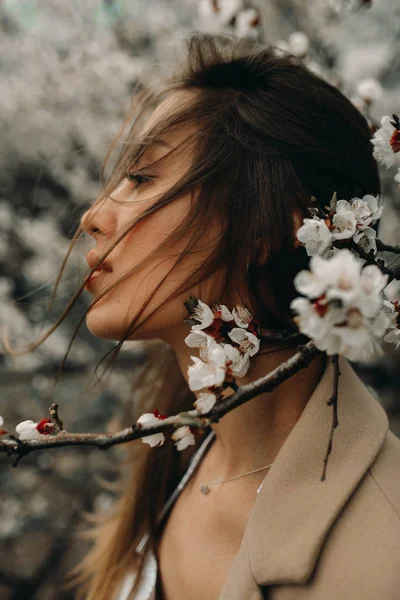 Portret van jonge vrouw onder bloeiende abrikozenbomen. — Stockfoto