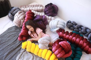 Çocuk kız pijama alışılmadık yastıklar arasında yatıyor.