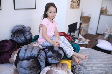 Çocuk kız pijama alışılmadık yastıklar arasında oynuyor.