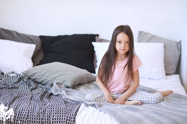 女の子はパジャマのベッドの上に座る. — ストック写真