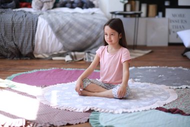 Çocuk kız yapar Yoga egzersizleri üzerinde bu mat.