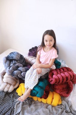 Çocuk kız pijama alışılmadık yastıklar arasında oynuyor.