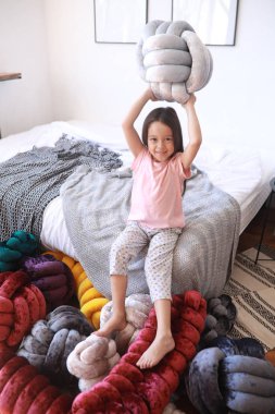 Çocuk kız pijama alışılmadık yastıklar arasında oynuyor.